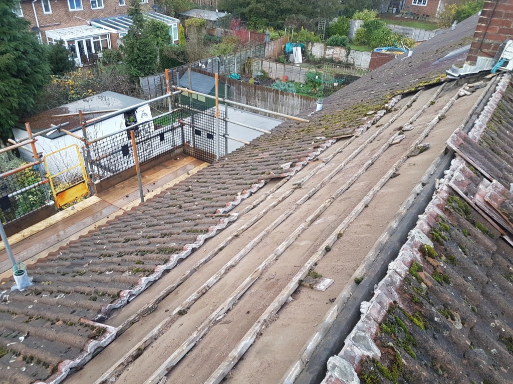 Old roof tiles and exposed ridge bedding during roof replacement in Langley Green, Crawley