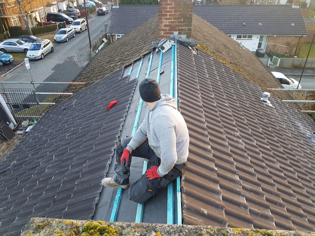 Replacement roof tiles being laid beside the prepared ridge
